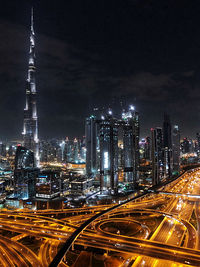 Illuminated modern buildings in city against sky at night