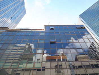 Low angle view of modern glass building against sky