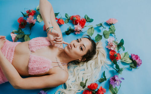 Portrait of woman lying down on floor by flowers