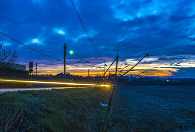 Electricity pylon on field against sky at sunset