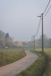 Road amidst field against clear sky