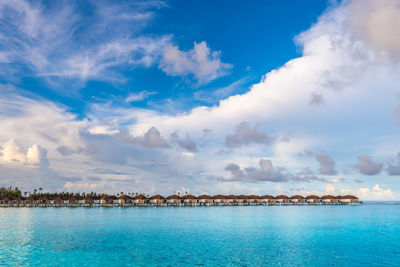 Scenic view of water villas in maldives with turquoise pristine water and dramatic sky