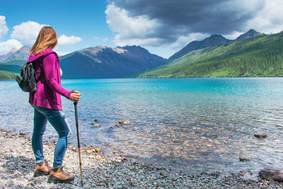 Rear view of woman standing on mountain against sky