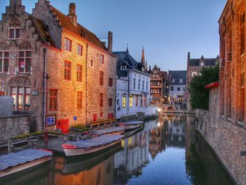 Boats moored in canal amidst buildings against clear sky