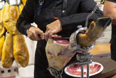 Photo of woman specialist in cutting serrano ham.