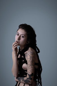 Portrait of sensuous naked young woman with tattoo over white background