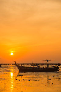 Silhouette boats moored on sea against orange sky