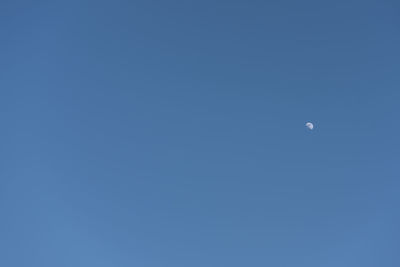 Low angle view of moon against clear blue sky