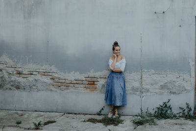 Portrait of young woman standing against wall