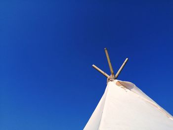 Low angle view of wind turbine against clear blue sky