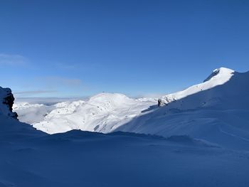 Scenic view of snowcapped mountains against blue sky