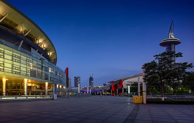 Illuminated city against clear blue sky