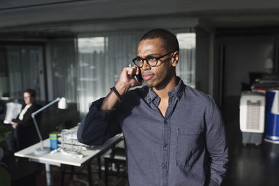 Businessman using phone while standing at office