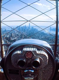 Close-up of coin-operated binoculars at empire state building against sky