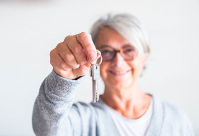 Close-up portrait of woman with arms raised against white background