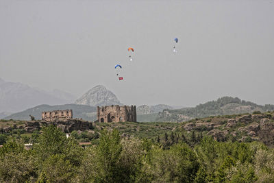 Hot air balloon flying over mountains against clear sky