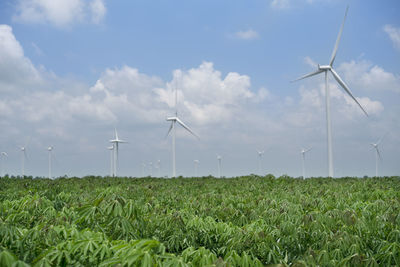 Windmills on field against sky