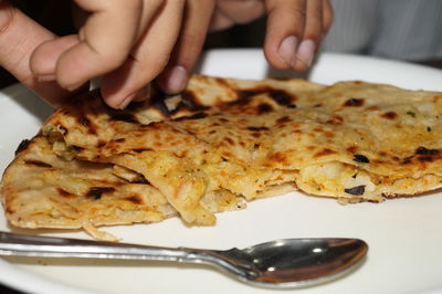 Close-up of hand holding bread in plate on table