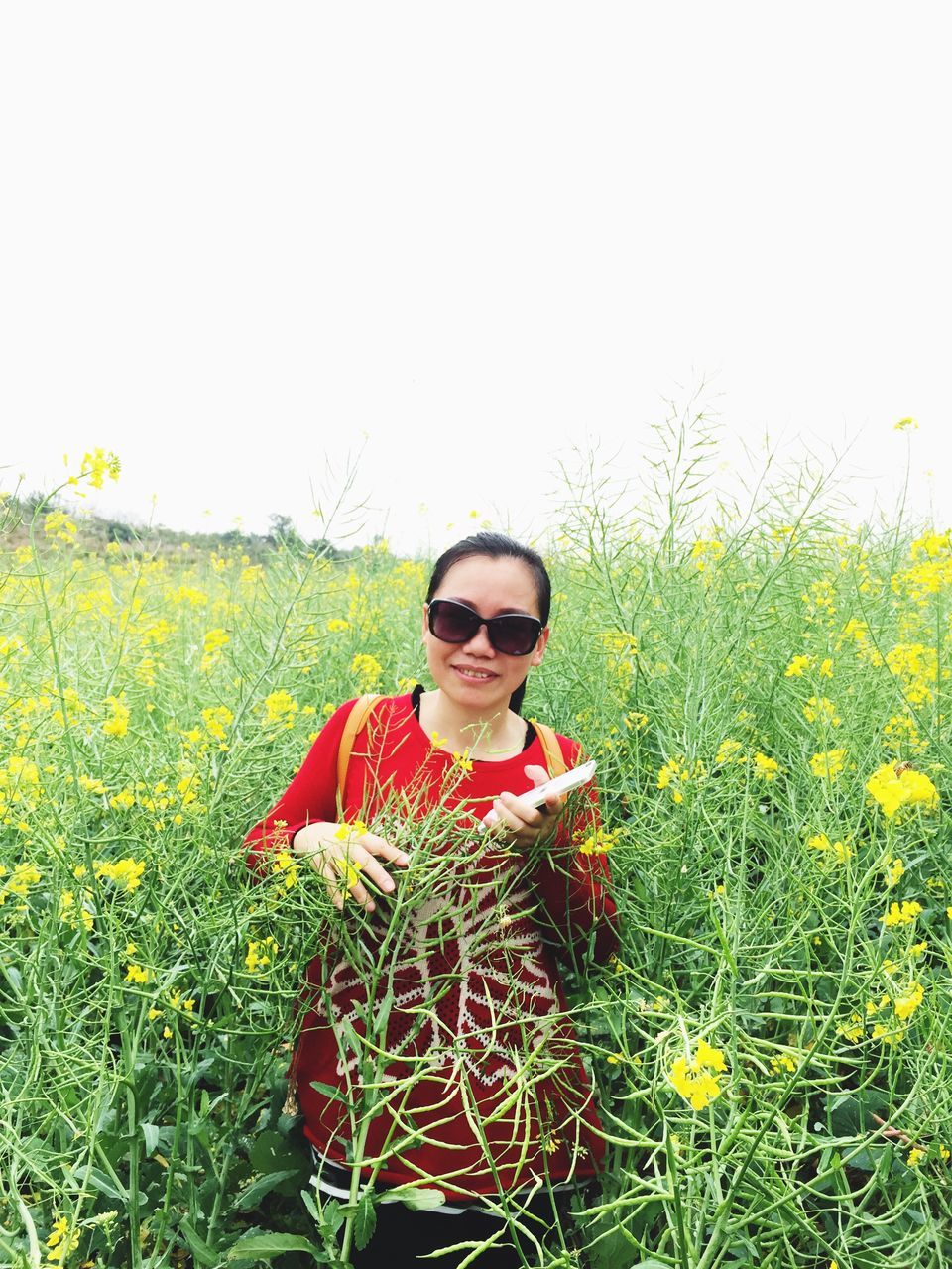 lifestyles, flower, person, casual clothing, leisure activity, young adult, field, clear sky, freshness, standing, plant, growth, waist up, smiling, beauty in nature, nature, young women, front view