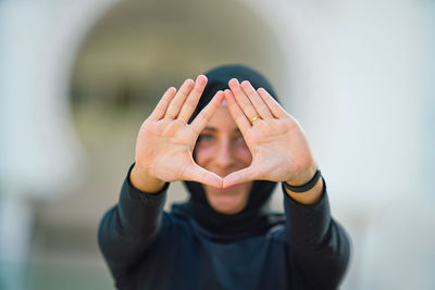 Portrait of young woman in hijab gesturing while outdoors