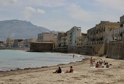 People at beach lying on the sand against sky