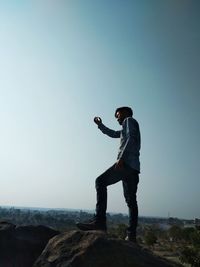 Man standing on rock against clear sky