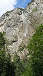 Low angle view of waterfall amidst rocks against sky