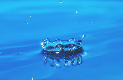 Close-up of drop falling on blue water