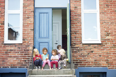 Children sitting on steps and eating apples