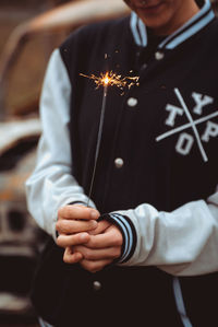 Midsection of man holding sparkler