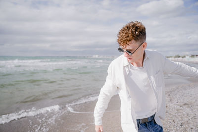 A young guy in motion at sea with curly hair on his head and wearing round sunglasses