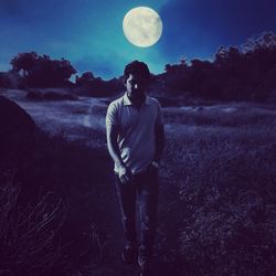 Full length of man standing on field against moon at night