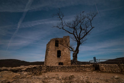 Low angle view of old building on field against sky