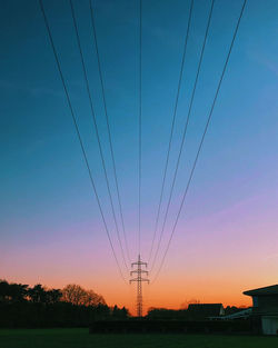 Silhouette electricity pylon against romantic sky at sunset