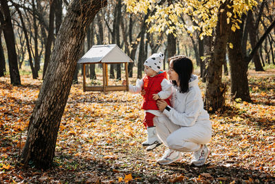 Family fall activities. happy family mom and toddler baby girl feeding the birds outdoors in fall