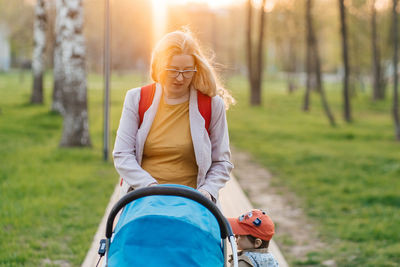 Mom walks with stroller and toddler son in the park