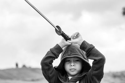 Portrait of boy holding sword against sky