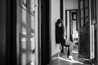 Side view of young woman standing by window