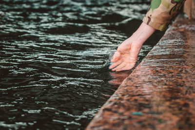 The girl dipped her hand into the water. touching the river with the palm of your hand 