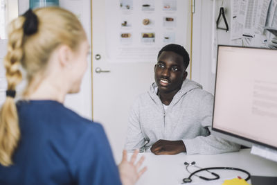 Teenage male patient listening to female nurse during consultation at hospital