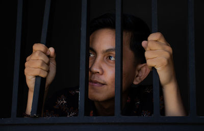 Portrait of young man looking through window