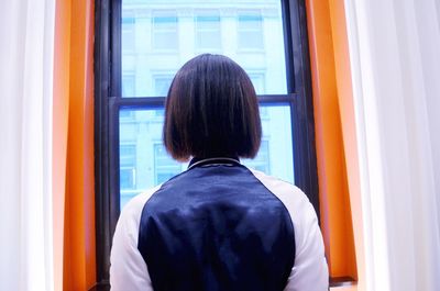 Rear view of man looking through window