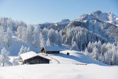 Picturesque winter scene with an old alpine hut and snowy mountain peaks