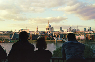 Tourists looking at city buildings against cloudy sky