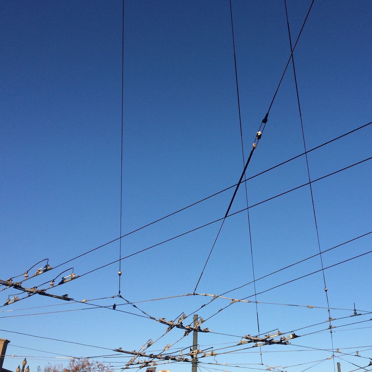 blue, clear sky, low angle view, power line, cable, copy space, connection, electricity, power supply, electricity pylon, outdoors, built structure, technology, day, no people, fuel and power generation, high section, power cable, sky, vapor trail