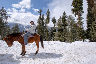 Man riding horse on snow covered field