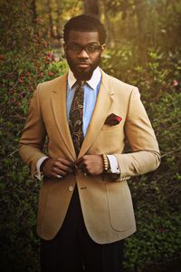 Portrait of young man standing by plants at park