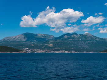 Scenic view of sea and mountains against blue sky