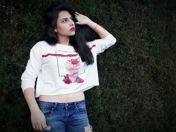 Portrait of young woman standing against grass