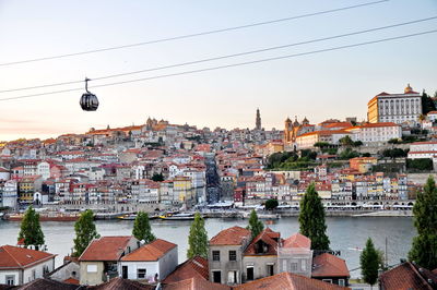 Overhead cable car over river against sky in city